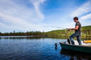 jovem adulto pescando truta em um lago calmo foto