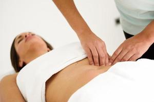 mãos massageando o abdômen feminino. terapeuta aplicando pressão na barriga. foto