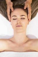 jovem loira recebendo uma massagem na cabeça em um centro de spa. foto