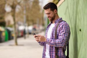 jovem sorridente olhando seu telefone inteligente no meio urbano. conceito de estilo de vida. foto