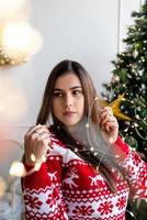 jovem com chapéu de Papai Noel e suéter segurando lindas luzes de natal foto