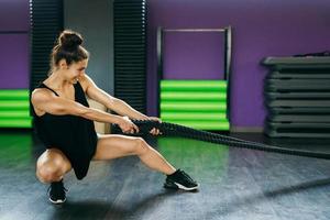 mulher jovem e atlética, usando cordas de treinamento em um ginásio.