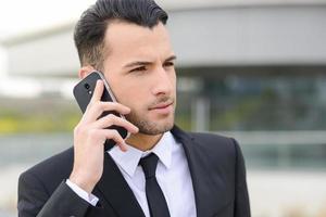 atraente jovem empresário ao telefone em um prédio de escritórios foto