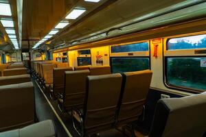 público trens dentro Java, Indonésia estão esvaziar do passageiros dentro a tarde quando a Sol conjuntos. a trem transporte estava quieto e muitos passageiro assentos estavam esvaziar foto