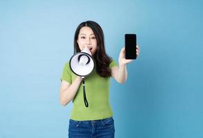 retrato de menina asiática segurando um alto-falante, isolado em um fundo azul foto