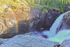 árvore quebrada morta caída ao lado da cachoeira de rjukandefossen do arco-íris. foto