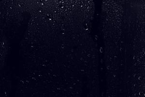 gotas de água sobre fundo preto. gotas de água de orvalho abstratas em um vidro de janela para efeito de sobreposição de foto ou dando um efeito fresco na maquete de bebidas. tiro macro da gota de chuva detalhada.