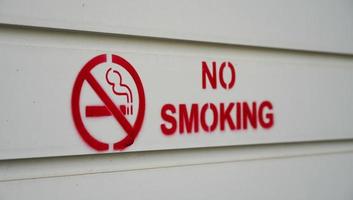 um sinal de proibido fumar em vermelho está impresso na parede branca. o cuidado em locais públicos para proibir as pessoas de fumar nessas áreas. foto