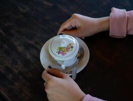 uma xícara de café quente está sobre a mesa. uma garota tem uma bebida saborosa na mão. uma espécie de aproveitar o tempo de lazer. foto