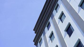 um arranha-céu que tem muitos materiais de vidro com um fundo de céu azul. o prédio alto na zona urbana. foto