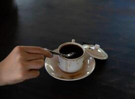 uma xícara de café quente está sobre a mesa. uma garota tem uma bebida saborosa na mão. uma espécie de aproveitar o tempo de lazer. foto