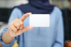 uma senhora com uma roupa azul está mostrando um espaço em branco vazio. uma maquete que é adequada para uso comercial ou maquete de identidade. foto