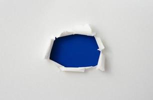 moldura de papel rasgado com os lados rasgados. um buraco azul rasgado no papel branco. papel rasgado realista com as bordas rasgadas para espaço de cópia e texto. foto
