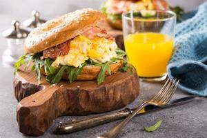 bagels com ovos mexidos, rúcula e bacon frito foto