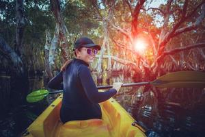 mulher navegando de caiaque no mar em grande habitat de floresta de mangue foto