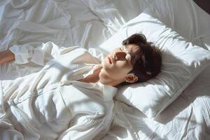 ásia homem 20 yo dentro uma branco roupas deitado baixa em branco cama com branco cobertor, alegremente dormindo foto