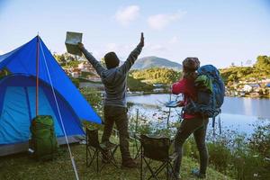 casal asiático acampa na montanha na aldeia superior perto do lago, conceito de viagens de acampamento, mapa de conceito de relaxamento de viagens. foto