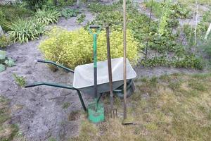 uma ferramenta de jardim e um carrinho de mão usados em um terreno pessoal. foto
