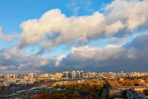 a colorida paisagem urbana do outono kyiv, os raios de sol por trás das nuvens cinzentas captam e iluminam intensamente a folhagem laranja do parque da cidade. foto