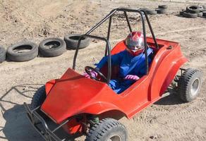 corrida de adolescente em carrinho infantil pela pista de areia foto