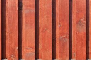 a textura da nova cerca de madeira marrom-vermelha aos raios de sol. foto