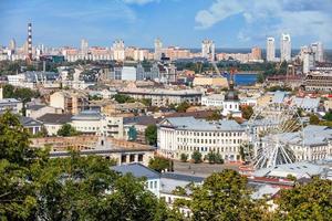 a paisagem do verão kyiv com vista para o antigo bairro de podil com uma roda gigante, edifícios novos e antigos e um novo bairro no horizonte. foto