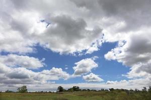 o céu azul emerge através de nuvens densas sobre a campina de verão foto