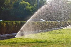 o gramado verde é regado com um poderoso sistema de irrigação. foto