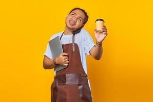 retrato de homem asiático bonito ocupado atendendo chamadas. ambas as mãos carregando um laptop e uma xícara de café foto