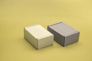 close-up mock up de caixas de papelão com espaço de cópia. duas caixas corton marrons e brancas sobre um fundo amarelo. conceito de embalagens, presentes, entrega.