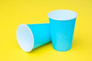 dois copos de papel azuis em fundo amarelo foto