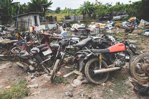 sucata com ferrugem velha de motocicleta de motor, pilha de aros de roda de metal enferrujado nos resíduos de veículos foto