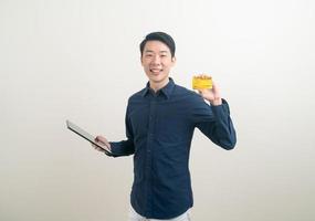 retrato jovem asiático segurando um cartão de crédito e um tablet foto