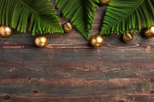 folha de pinheiro de natal com decoração de bugiganga dourada na mesa de madeira foto