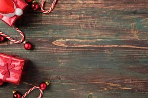 bugiganga vermelha de natal, caixa de presente, decoração de bastão de doces no fundo de madeira da mesa foto