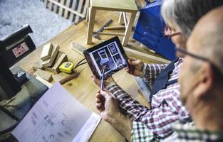 casal sênior em carpintaria procurando tablet foto