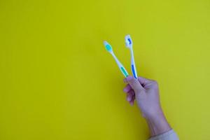 mão segurando uma escova de dentes com os dentes isolados em um fundo amarelo com o tema saúde foto