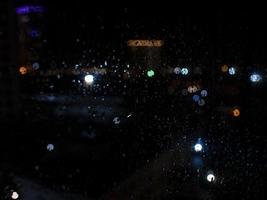 A chuva cai na janela com as luzes do bokeh da rua foto