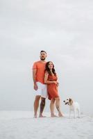 jovem casal em roupas laranja com cachorro foto