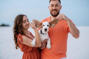 jovem casal em roupas laranja com cachorro foto