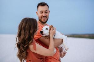 jovem casal em roupas laranja com cachorro foto