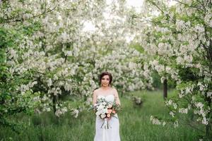 noiva em um vestido branco com um grande buquê de primavera foto