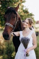 garota com um vestido de verão branco em uma caminhada com cavalos marrons foto