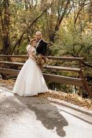 caminhada da noiva e do noivo pela floresta de outono foto