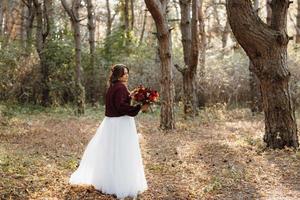 garota em um vestido de noiva na floresta de outono foto