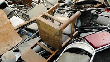 a pilha de cadeiras dobráveis quebradas. cadeira dobrável descartada no lixo bagunçado. a mobília escolar envelhecida no lixo. foto