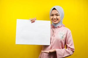 muito jovem mulher muçulmana alegre segurando uma faixa vazia em branco, cartaz, quadro branco, placa de sinalização em branco, placa de propaganda branca, apresentando algo no espaço da cópia, promoção foto