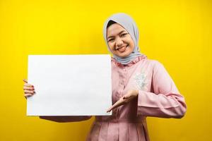 muito jovem mulher muçulmana alegre segurando uma faixa vazia em branco, cartaz, quadro branco, placa de sinalização em branco, quadro de propaganda branco, apresentando algo no espaço da cópia, promoção foto