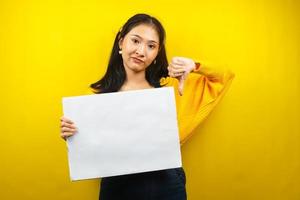 Mulher jovem bonita e fofa não gosta, mão segurando uma faixa vazia em branco, cartaz, quadro branco, placa de sinalização em branco, quadro de propaganda branco, apresentando algo no espaço da cópia, promoção foto