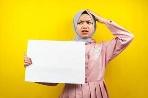 muito jovem mulher muçulmana chocada, surpresa, uau, mão segurando uma faixa vazia em branco, cartaz, quadro branco, placa de sinalização em branco, placa de propaganda branca, apresentando algo no espaço da cópia, promoção foto